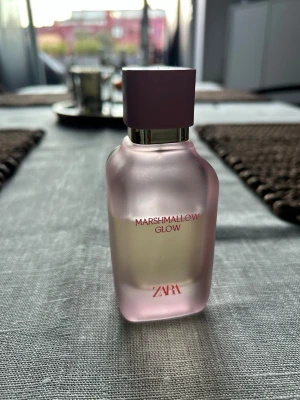 ZARA Marshmallow Glow parfym - Säljer en ZARA Marshmallow Glow parfym i en snygg frostad glasflaska med ljusrosa ton och matchande rosa kork. Flaskan har en modern, mjukt fyrkantig form och silverdetalj vid halsen. Perfekt för dig som gillar söta dofter och stilren design. Drygt 50% kvar (se bild)