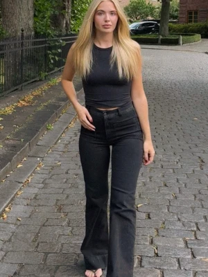 Svarta bootcut jeans med hög midja - Jeanerica St Monica strl 25/34, ett par svarta bootcut jeans med hög midja och klassisk femficksdesign. Jeansen har en snygg passform som sitter tajt över höfterna och låren och släpper ut nedtill. 