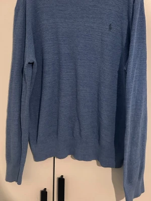 Polo Ralph Lauren tröja - Tunn blå stickad tröja från Polo Ralph Lauren i linne och bomull.  Tröjan har rund halsringning och långa ärmar. Perfekt till både vår och höst/vinter. Perfekt för lager på lager och enkel att matcha med jeans eller chinos. Inga defekter 