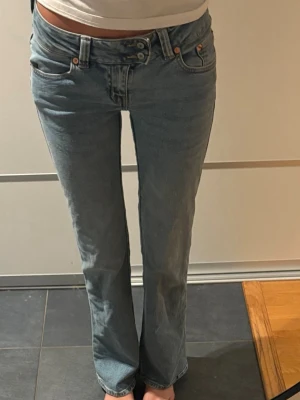 Ljusblå bootcut jeans med brodyr - Säljer ett par ljusblå bootcut jeans med snygg broderad detalj på bakfickan. Jeansen har klassisk femficksmodell, normal midja och stängs med knapp och dragkedja. Perfekta för dig som gillar en avslappnad men trendig look.