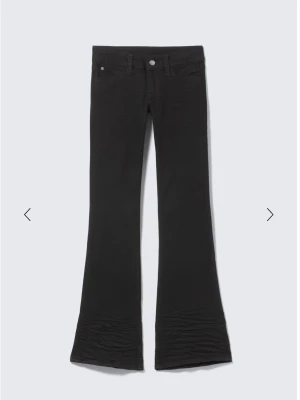Svarta bootcut jeans Cheap monday  - Säljer ett par svarta bootcut jeans med utsvängda ben och en cool rosa patch med döskalle på bakfickan. Jeansen har klassisk femficksdesign och är tillverkade i stretchigt material för skön passform.