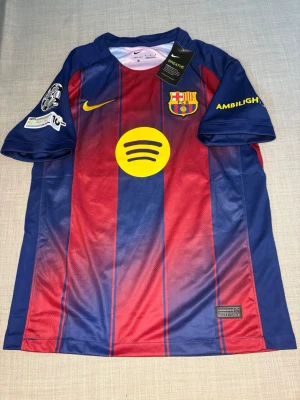 FC Barcelona matchtröja Lamine Yamal - Säljer en FC Barcelona matchtröja från Nike med Lamine Yamal och nummer 10 på ryggen. Tröjan är blå och röd med gula detaljer, klubbmärke och sponsorer på bröstet. Tillverkad i lätt och ventilerande material, perfekt för fotboll eller träning.