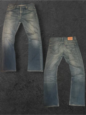 Sjukt feta Levi's 507 i bootcut  - Klassiska blå jeans från Levi's modell 507 med raka ben och snyggt slitna detaljer. Jeansen har fem fickor, knappgylf och den ikoniska läderlappen bak i midjan. Perfekta för en avslappnad och tidlös stil.