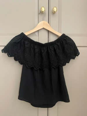 Offshoulder topp - Säljer en svart offshoulder topp med bred volangkant i broderi. Storlek 34, XS ifrån ginatricot. Skriv för frågor eller prisförslag 💗