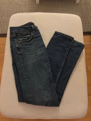 Nudie jeans lean dean  - Säljer ett par blå jeans i slim passform med klassisk femficksdesign. Jeansen har normal midja och dragkedja med knapp. Otroligt bra skick