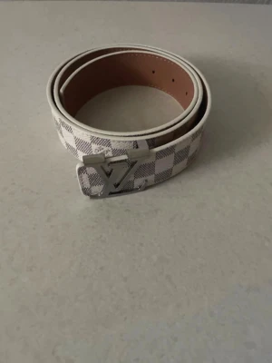 Rutigt bälte med silverfärgat spänne - Snyggt bälte i vitt och grått med rutigt mönster och ett stilrent silverfärgat spänne. Perfekt accessoar för att lyfta din outfit med en modern touch. Bältet har klassisk design och passar till många olika stilar.