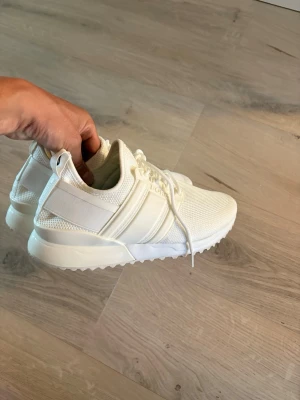 Vita sneakers Björn Borg R220 Low - Snygga vita sneakers från Björn Borg, modell R220 Low. Skorna har en sportig design med mesh- och syntetmaterial, samt tydliga vita detaljer och snörning. Perfekta för en clean och fräsch stil. Sulan är tjock och ger bra komfort.