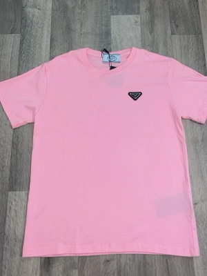 Prada  - Säljer en stilren rosa Prada t shirt, helt ny och kommer med alla tillbehör som syns på bilden