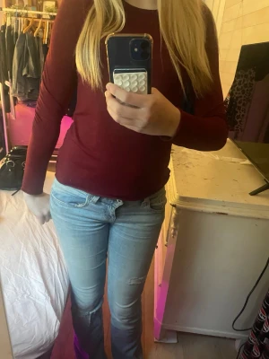 Mörkröd långärmad topp - En enkel och stilren mörkröd långärmad topp med rund halsringning. Toppen har en tight passform och är perfekt att matcha med jeans eller kjol. Materialet känns mjukt och stretchigt, vilket gör den bekväm att bära hela dagen.