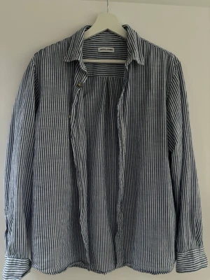 Randig skjorta från Jack & Jones - Säljer en snygg randig skjorta från Jack & Jones i vitt och blått. Skjortan har klassisk krage, långa ärmar och knappar framtill. Tillverkad i ett lätt och skönt bomullsmaterial, perfekt för en avslappnad men stilren look.