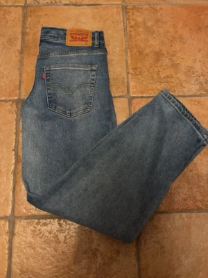 Blå Levi's raka jeans - Klassiska blå jeans från Levi's med rak passform och hög midja. Jeansen har fem fickor, Levi's ikoniska röda etikett på bakfickan och patch med logga bak i midjan. Tillverkade i slitstark denim som ger en tidlös look.