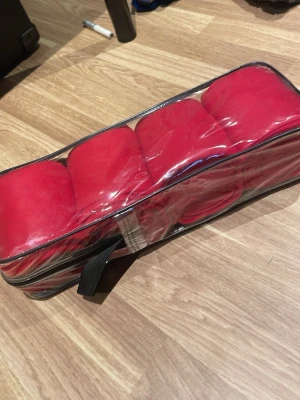 Röda fleecelindor  - Fyra stycken röda fleecelindor i en genomskinlig förvaringsväska med dragkedja och handtag. Perfekt för ridning eller annan aktivitet där lindor behövs. Mjukt och följsamt material.
