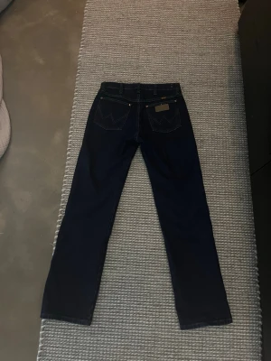 Mörkblå raka jeans - Säljer ett par mörkblå jeans med rak passform och klassiska fem fickor. Jeansen har kontrastsömmar och en patch bak i midjan. Perfekta till en avslappnad stil och tillverkade i denim. Nya och använda kanske 3 gånger.