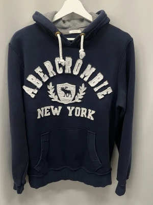 Abercrombie & fitch hoodie - Säljer nu denna abercrombie & fitch hoodien i storlek M | jag är 185 cm och väger ca 76 kg och den sitter lite litet. Fint skick utan defekter. Tjock och skön perfekt nu till kallare dagar.