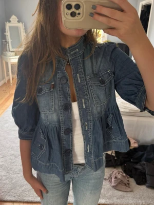 Kort jeansjacka med puffärm - Trendig blå jeansjacka med puffärmar och markerad midja. 