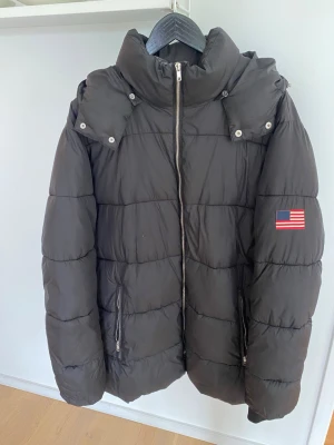 Svart pufferjacka Iconic Sport XL - Säljer en svart pufferjacka från Iconic Sport i storlek XL men passar mig som har storlek M. Två fickor med dragkedja. Vadderad. Fyllning: Polyester. 