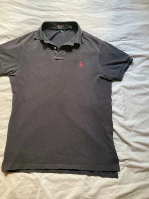 Svart pikétröja från Polo Ralph Lauren - Snygg Polo Ralph Lauren piké, klassisk modell som passar till nästan alla tillfällen. Använd ett fåtal gånger. 