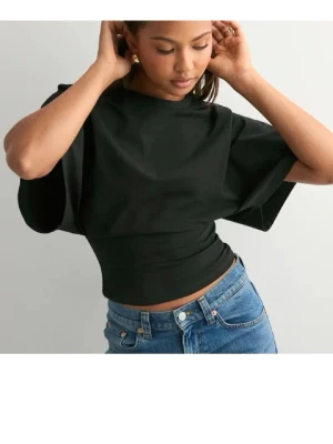 Svart croppad topp med vida ärmar - Snygg svart croppad topp med bred midjeresår och vida, korta ärmar. Toppen har en enkel och clean look som passar perfekt till jeans eller kjol. Tillverkad i mjukt bomullsmaterial för en bekväm känsla. Den har aldrig används utan vara legat i garderoben. 💗