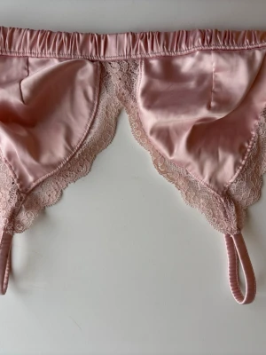 Rosa spetsbralette med satin från Monki, storlek S - Söt rosa bralette i satin med tunna axelband och vacker spetskant runt kuporna. Mjuk och följsam modell utan bygel. Från Monki, storlek S. Perfekt skick! Använd någon enstaka gång.