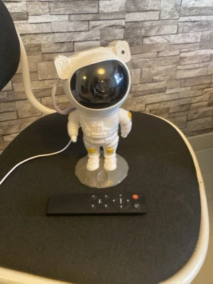 Astronaut lampa med fjärrkontroll - Cool astronautformad lampa i vitt och svart plast med gulddetaljer. Lampan har en futuristisk design och styrs enkelt med medföljande fjärrkontroll. Perfekt som dekoration eller mysbelysning i rummet. Drivs via USB-kabel.