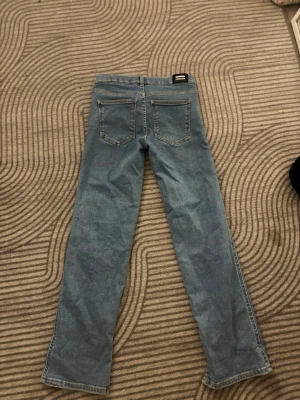 Blå raka jeans - Snygga blå jeans med rak passform. Klassisk femficksmodell med silverfärgad knapp och ljusblå sömmar. 