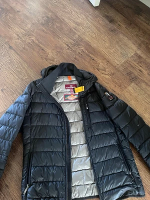 Svart dunjacka från Parajumpers - Snygg svart dunjacka från Parajumpers med lättviktigt material och quiltad design. Jackan har huva, dragkedja den har ett litet håll som är sytt som man ser på ena bilden