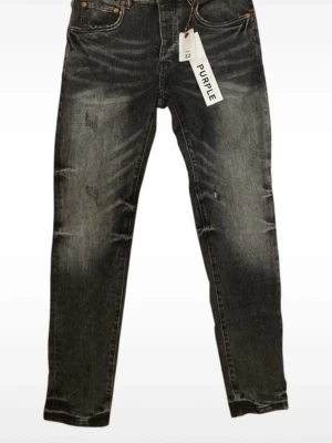 Svarta slim fit jeans från Purple - Snygga svarta slim fit jeans från Purple med slitna detaljer och tvättad look. Jeansen har klassisk femficksmodell, knappgylf och raka ben. Perfekta för dig som gillar en trendig och avslappnad stil.