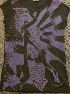 Svart t-shirt med lila grafiskt tryck - Svartlila t-shirt med två kvinnor på, står storlek M men tycker XS