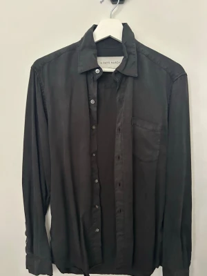 Svart skjorta från A Day's March - Klassisk svart skjorta från A Day's March i storlek Small. Skjortan har lång ärm, bröstficka och knappar framtill. Perfekt till jeans eller chinos för en clean och stilren look.