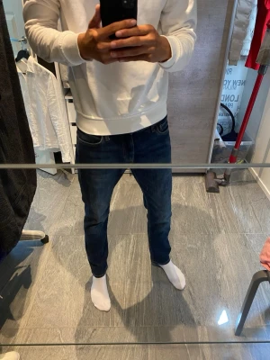 Mörkblå raka jeans herr - Säljer ett par mörkblå jeans med rak passform och klassiska fem fickor. Jeansen har en snygg tvätt och kontrastsömmar. Perfekta till en avslappnad stil och passar till det mesta. Materialet är troligtvis bomull med lite stretch.