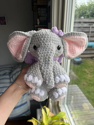 Virkad ljusgrå elefant🐘🎀 - Supersöt virkad elefant av mitt eget mönster ”Ellie the elephant”! Har en supersöt rosett runt halsen och på huvudet. Denna elefant är ljusgrå med vita och ljusrosa detaljer med lila rosetter🩶💜🎀 !OBS, innehåller säkerhetsögon som ej rekommenderas för barn under 3 år! 