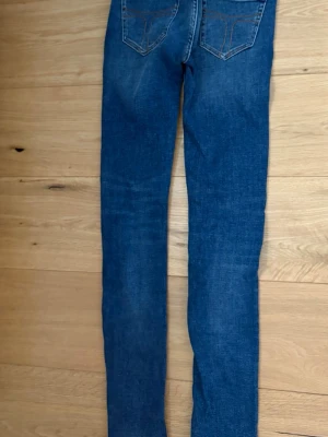 Mörkblå skinny jeans med kontrastsömmar - Säljer ett par mörkblå skinny jeans med kontrastsömmar och klassiska bakfickor. Jeansen har en smal passform och är tillverkade i stretchigt denimtyg för extra komfort. Perfekta till en avslappnad streetstyle-look.