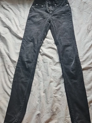 Svarta raka jeans med hög midja - Säljer ett par svarta jeans med hög midja och raka ben. Jeansen har klassisk femficksdesign och silverfärgade nitar. Materialet är denim i bomull. Perfekta för en avslappnad och stilren look.
