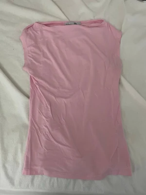 Ljusrosa ärmlös topp från 157 - Söt ljusrosa topp från 157 i mjuk bomull. Modellen är ärmlös med enkel och clean design, perfekt att styla med jeans eller kjol. Toppen har rund halsringning och är figurnära i passformen.