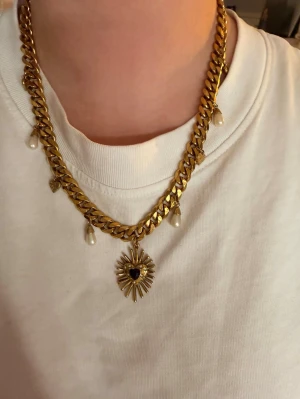 WOS veja valentina necklace guld - Säljer ett chunky guldigt halsband med dekorativa pärlor och små hjärtan. Halsbandet har ett stort solformat hänge med svart hjärtdetalj i mitten. Perfekt statement piece för dig som vill sticka ut. Använd fåtal gånger och har inga defekter 💕