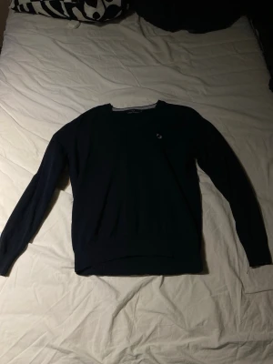 Mörkblå tröja med rund hals - En stilren mörkblå tröja från fred Perry. Passar mycket bra bara som eller men de skjorta under. Väldigt liten i storlek. Så skulle säga att den passar medium bättre 