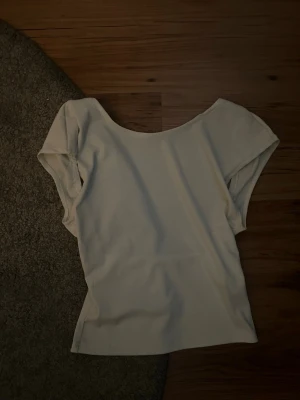 Vit ribbad topp från SHEIN - Säljer en enkel och stilren vit ribbad topp från SHEIN i storlek XS. Toppen har korta ärmar och en bred, rundad halsringning. Perfekt att matcha med jeans eller kjol för en clean look.