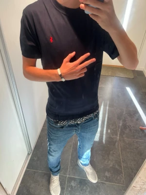 Ralph Lauren t-shirt - Snygg mörkblå t-shirt med en liten röd broderad logga på bröstet. Klassisk rund hals och korta ärmar. Perfekt basplagg som funkar till det mesta och är riktigt bekväm. Tillverkad i mjuk bomull för skön känsla hela dagen.