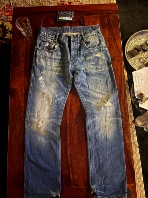 Blå slitna jeans med raka ben ifrån G STAR - Säljer ett par blå jeans med raka ben och slitna detaljer på både fram- och baksida ifrån G STAR. Jeansen har klassisk femficksmodell och ljus tvätt med tydliga slitningar för en avslappnad look. Perfekta för dig som gillar en casual och trendig stil. W30 L32