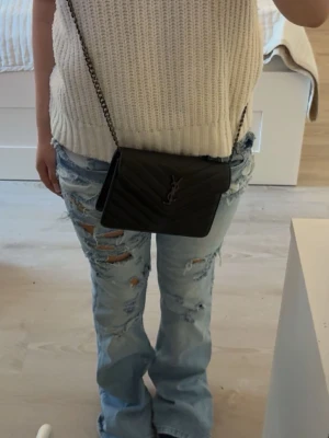Ljusblå slitna bootcut jeans - Säljer ett par ljusblå bootcut jeans med slitningar och hål på framsidan. hålen är gjorda själv 