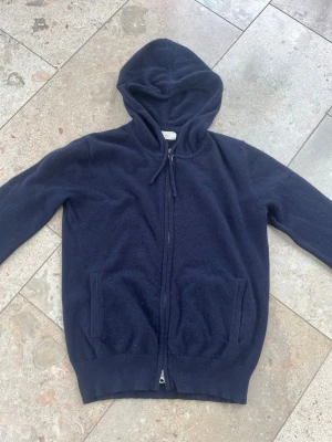 Mörkblå cashmere hoodie med dragkedja - Mysig mörkblå hoodie från Sayless i mjuk cashmere. Tröjan har dragkedja framtill, två fickor och en klassisk huva med snören. Tröjan är i storlek xxs men jag skulle säga att den är mer som xs. Säljer den för att den inte passar längre men den har fortfarande mycket mer att ge.