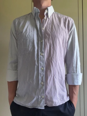 Randig ETON skjorta i blå/rosa/grå - Säljer en najs och unik randig Eton skjorta med en bröstficka. Som ny. Storlek L slim fit. Personen är 181cm och 80kg. Hör av er vid funderingar!😁