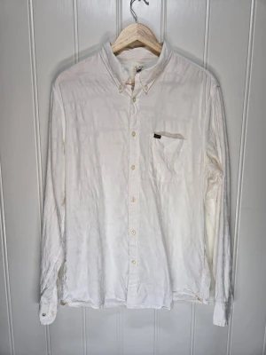 Vit skjorta från Lee i bomull - Klassisk vit skjorta från Lee i regular fit och Button down krage Snygg strukatur i skjortan. Lite äldre modell. Kanonsnygg till fest eller lite extra proper mitt på dagen. 
