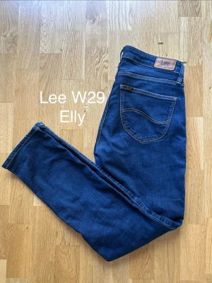 Mörkblå Lee Elly jeans W29 - Snygga mörkblå jeans från Lee, modell Elly. Klassisk femficksdesign med raka ben och bruna kontrastsömmar. Jeansen har Lee-lapp bak i midjan och är tillverkade i stretchigt denimtyg för extra komfort.