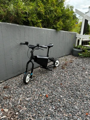 Svart eldriven minicykel - Säljer en svart eldriven minicykel med kompakt ram och små hjul. Cykeln har ett vadderat sadel, raka styren och en låda för batteri eller elektronik i mitten. Perfekt för kortare turer eller som smidig transportlösning. Endast upphämtning bromm