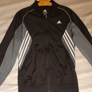 Adidas tracksuit top - Strlk: M - Skick: 7/10 - Unisex                                                                                         En snygg och litet ovanlig Adidas tröja som passar i alla sammanhang (typ... kanske.). Tröjan köptes second hand för ungefär ett år sen och är i ett väldigt bra skick (inga fläckar eller hål dvs). Den enda skavanken är zippern som saknar en liten del, men det syns knappt och påverkar inte tröjans funktion. Hör gärna av er om ni undrar något mer:)