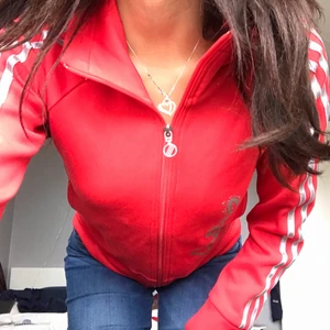 Hoddie - Röd adidas hoddie tröja med dragkedja. I mycket bra skick och perfekt för styla upp i cola stilar. (Obs! Säljer denna för en kompis så hennes namn står frt på lappen men funkar bra att ta bort de)🥰🤍