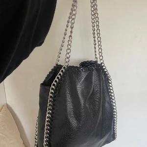 Svart kedje väska  - Säljer nu min supersnygga Stella mccartney liknande väska ifrån TIAMO! Väskan är väldigt rymlig och perfekt för att bära tex. Skolböcker och skoldatorn! Köp direkt för 499 eller buda privat!❤️ lånade bilder men skriv privat så får du egna! SÅLD VIA DIREKT KÖP