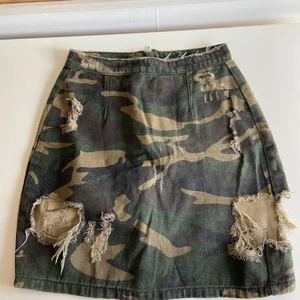 Kjol - Kort kjol i militärmönster i storlek 36, men skulle säga att den även passar någon med storlek 34. Två hål framtill som slitits upp en aning. Dragkedja baktill. Sitter väldigt bra!