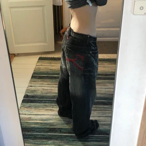 akademiks jeans strl 30 - Skit snygga Jeans med röda detaljer från akademiks. De är smala i midjan men väldigt baggy och långa i benen:)